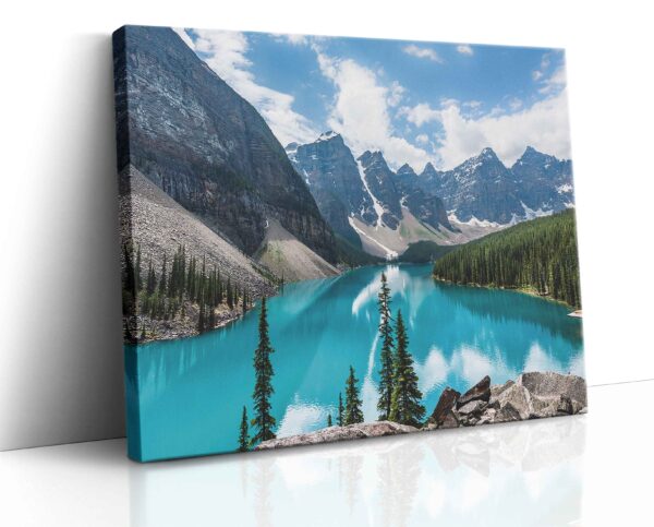 Panoramatický obraz jezera Moraine v národním parku Banff s tyrkysovou vodní hladinou obklopenou jehličnatými lesy a majestátními vrcholky kanadských Skalistých hor za svítání.
